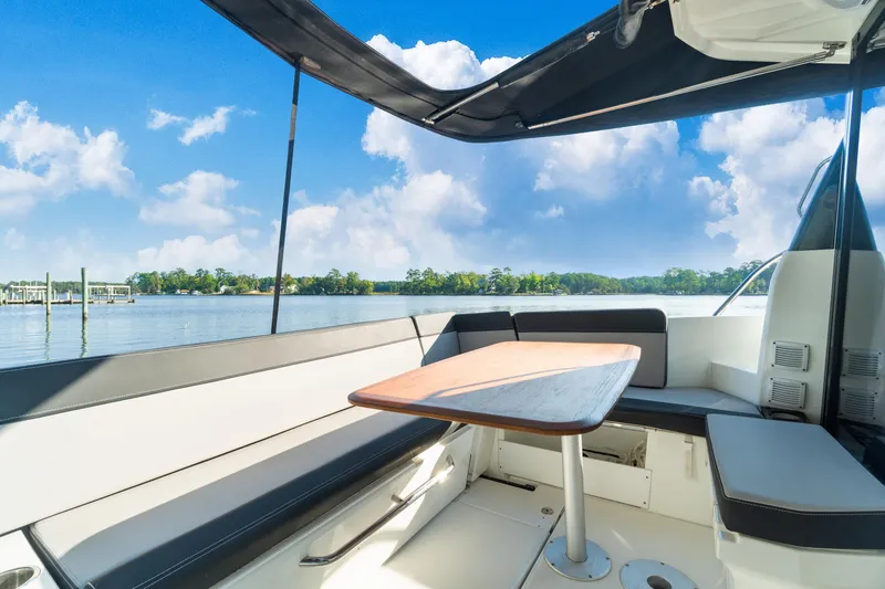 Slide: The Image of 2021 Jeanneau NC 1095 boat interior with seating and table, overlooking serene water. - 43