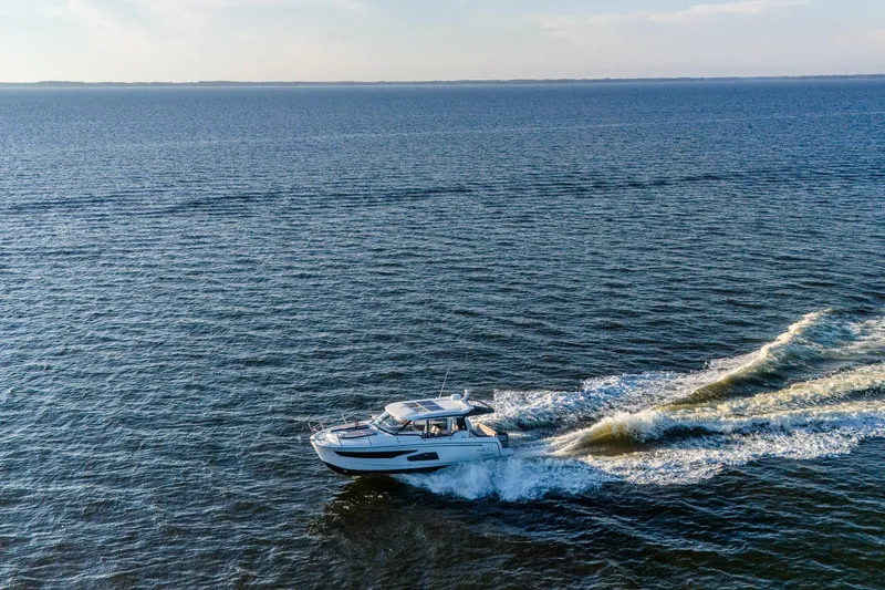 Slide: The Image of 2021 Jeanneau NC 1095 cruising on open water, creating a wake under clear skies. - 8
