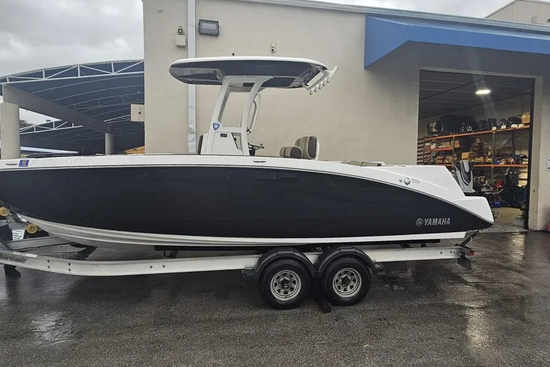 The Image of 2022 Yamaha Boats 255 FSH Sport E on trailer, parked outside a building. - 0