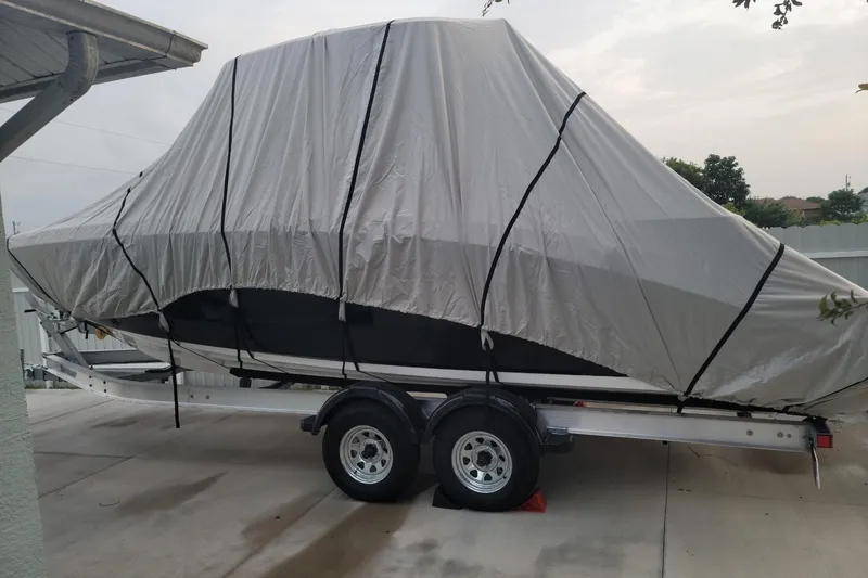 Slide: The Image of 2022 Yamaha Boats 255 FSH Sport E covered on trailer in driveway. - 10