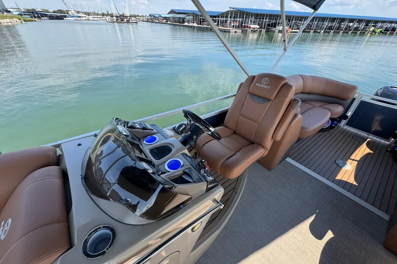 Slide: The Image of 2017 Regency 254 LE3 boat interior with luxurious seating and modern controls, docked by the water. - 10