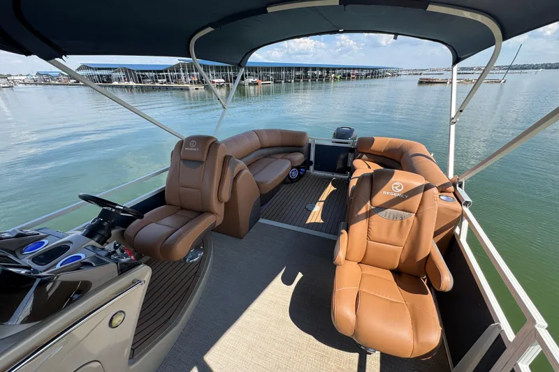 Slide: The Image of 2017 Regency 254 LE3 pontoon boat with tan seating, docked on a calm lake. - 19
