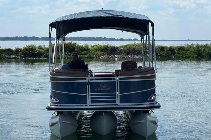 Slide: The Image of 2017 Regency 254 LE3 pontoon boat on a calm lake with canopy. - 2