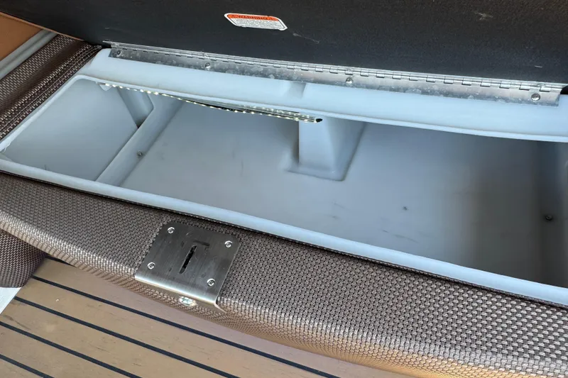 Slide: The Image of Open storage compartment in 2017 Regency 254 LE3 boat, featuring woven texture and metal latch. - 22