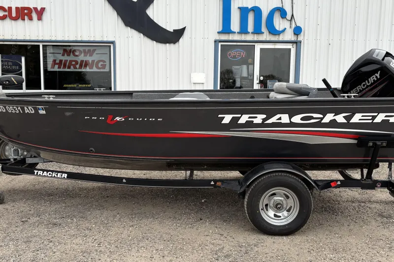 The Image of 2015 Tracker Pro Guide V-16 T boat on trailer, parked outside dealership. - 1