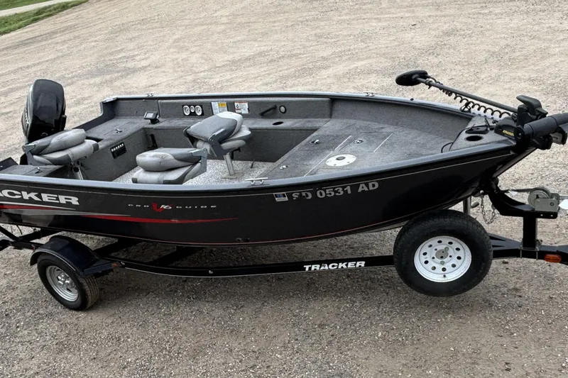 Slide: The Image of 2015 Tracker Pro Guide V-16 T fishing boat on trailer, parked on gravel. - 15