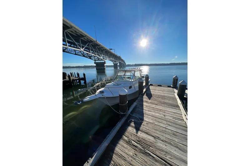 Slide: The Image of 2004 Parker 2510 Modified Vee Walkaround boat docked under a bridge in sunlight. - 14