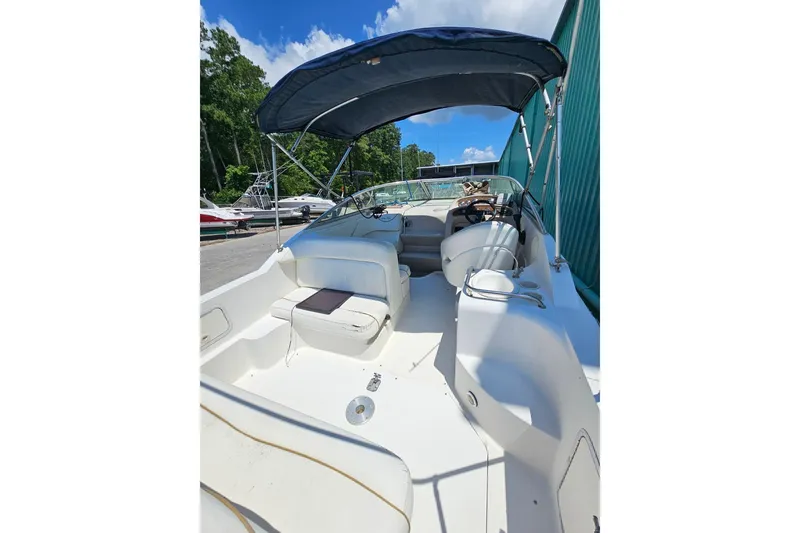 Slide: The Image of 2001 Sea Ray 260 Sundancer boat with canopy, docked under clear blue sky. - 34