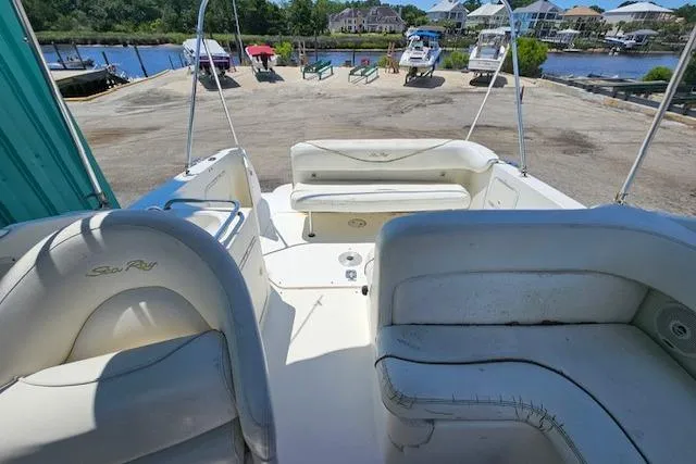 Slide: The Image of 2001 Sea Ray 260 Sundancer boat interior with white seating, docked near waterfront. - 38
