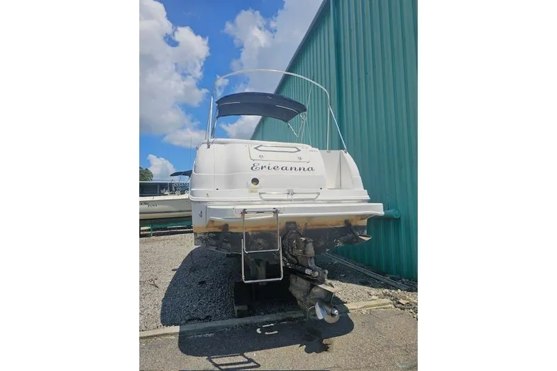 Slide: The Image of 2001 Sea Ray 260 Sundancer boat on trailer, parked near green building under blue sky. - 9