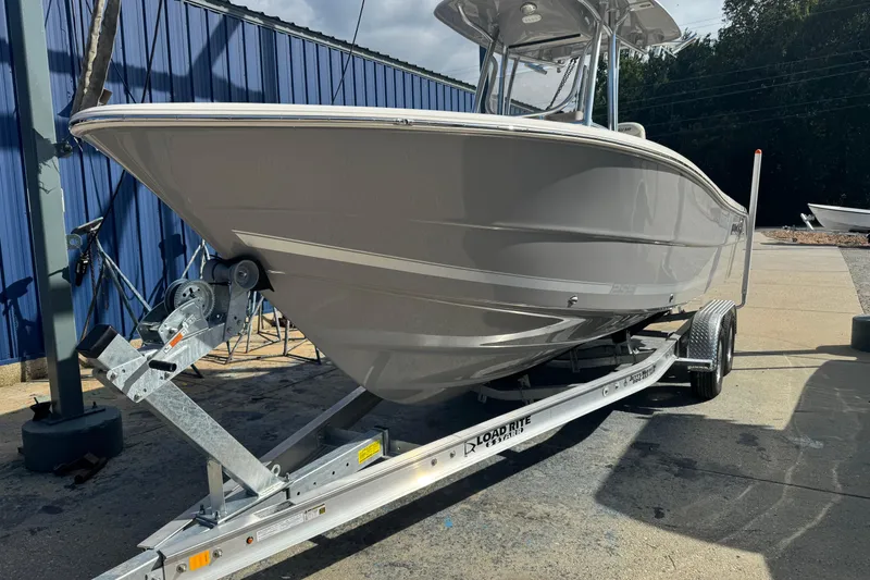 Slide: The Image of 2026 Bulls Bay 255 boat on trailer, parked outdoors near blue building. - 2