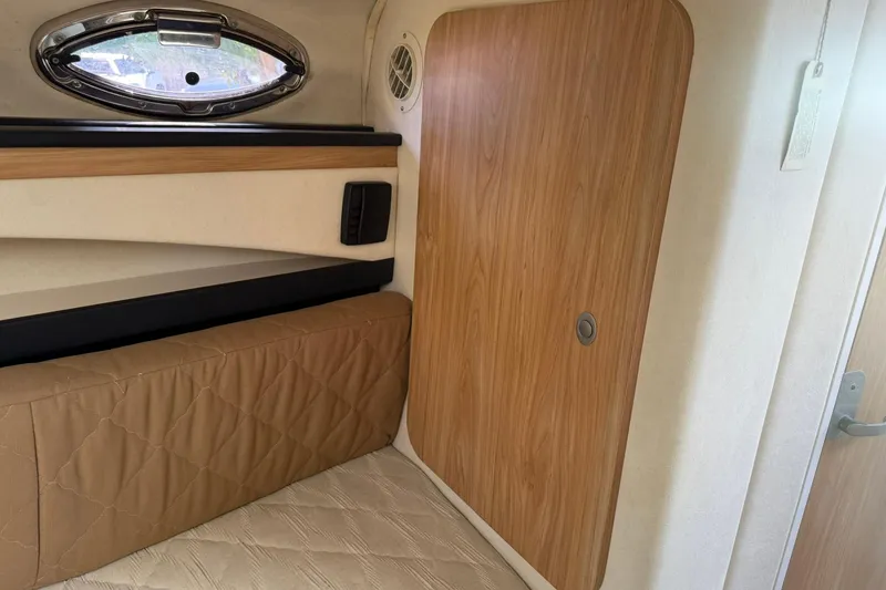 Slide: The Image of Interior cabin of 2006 Sea Ray 270 Amberjack with wood paneling and porthole window. - 26
