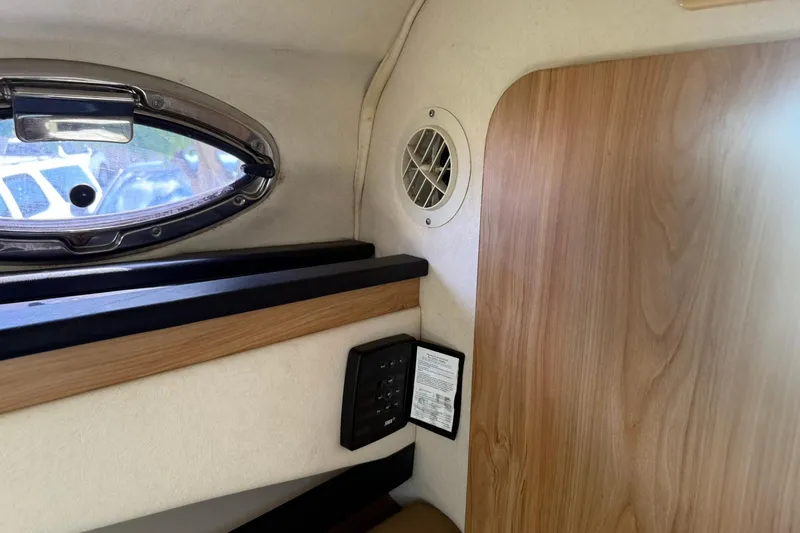 Slide: The Image of Interior cabin of 2006 Sea Ray 270 Amberjack with wood paneling and porthole window. - 34