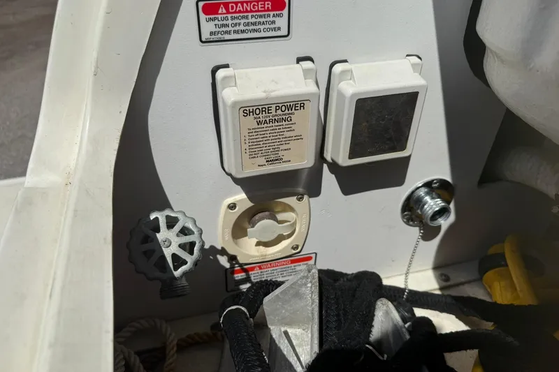 Slide: The Image of 2006 Sea Ray 270 Amberjack shore power connections and warning labels on boat deck. - 42