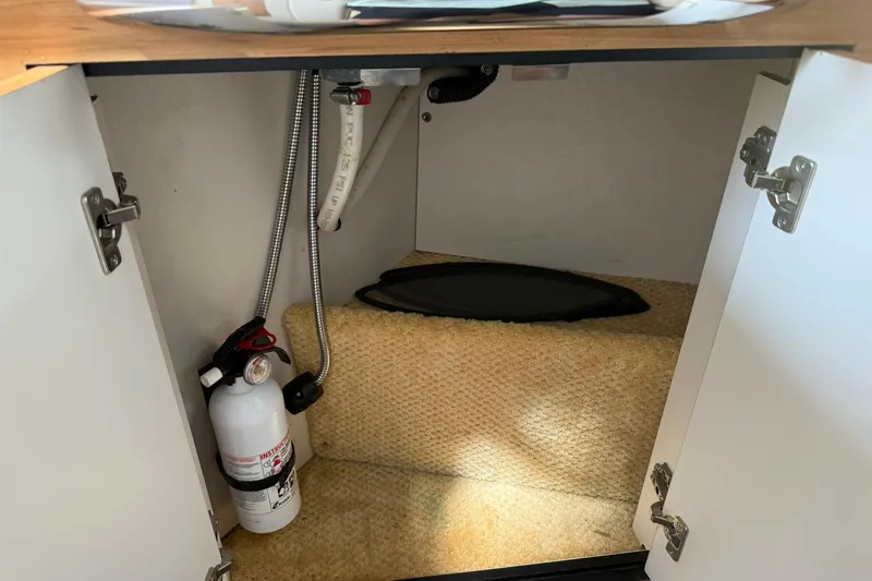 Slide: The Image of Open cabinet on 2006 Sea Ray 270 Amberjack boat, showing fire extinguisher and plumbing. - 59