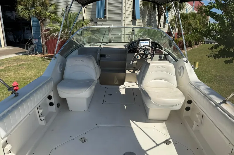 Slide: The Image of 2006 Sea Ray 270 Amberjack boat interior with seating and steering wheel, docked outdoors. - 64