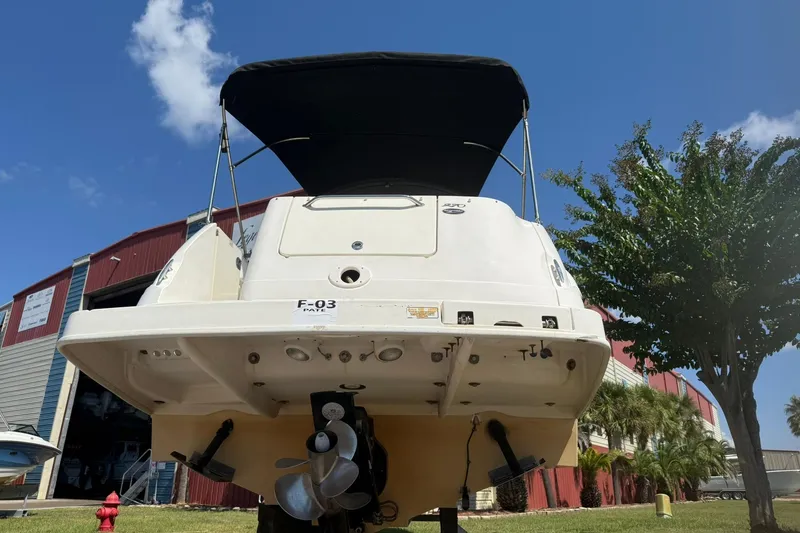 Slide: The Image of 2006 Sea Ray 270 Amberjack boat with canopy, docked near a red building and trees. - 7