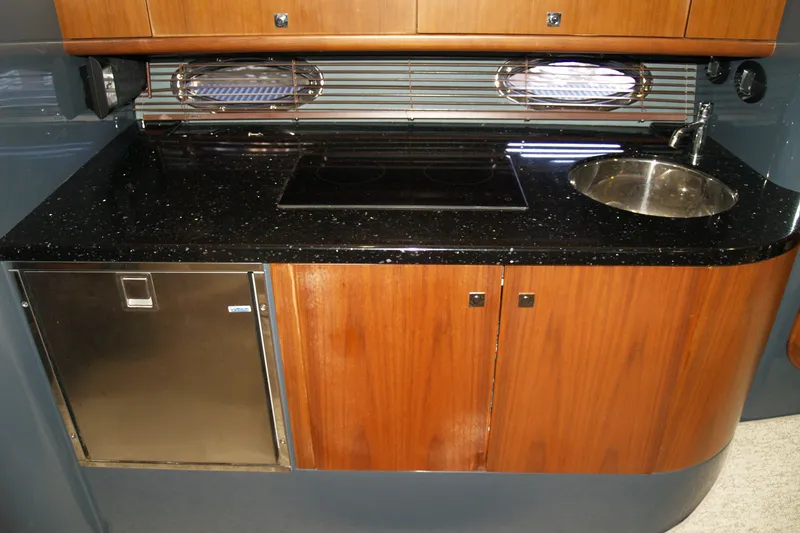 Slide: The Image of 2012 Hunton XRS 43 yacht kitchen with wooden cabinets, black countertop, and stainless steel sink. - 6