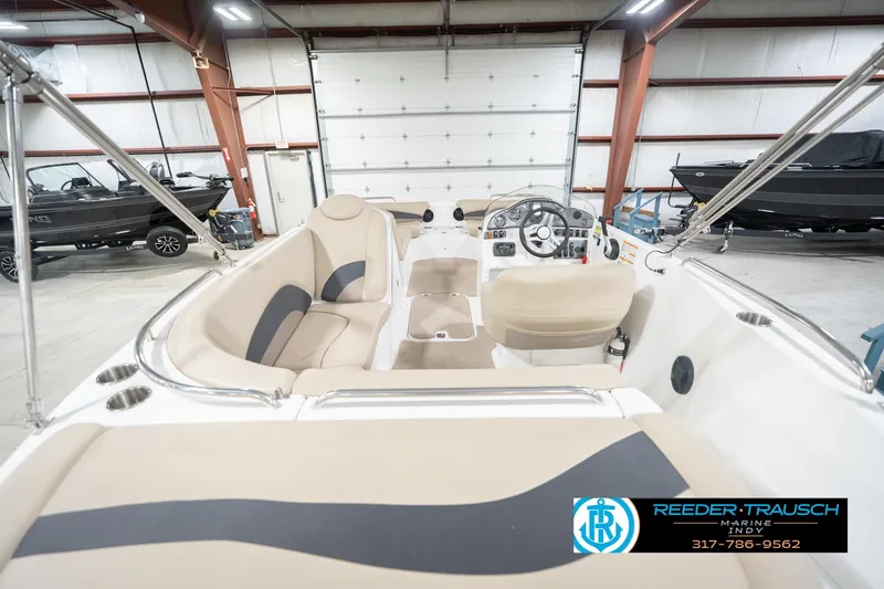 Slide: The Image of 2017 Hurricane SunDeck Sport 202 OB boat interior in showroom, featuring beige seating and steering console. - 16