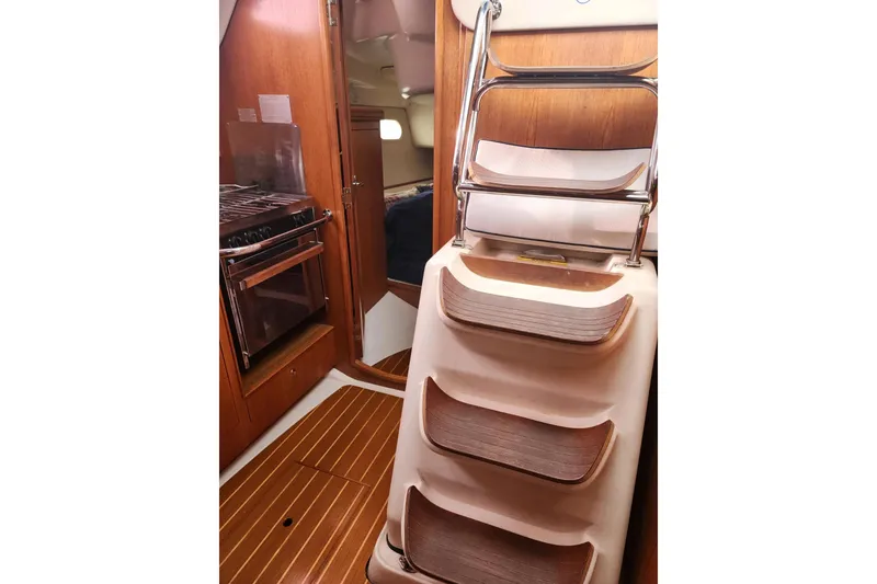 Slide: The Image of Interior of 2003 Hunter 386 sailboat with wooden steps and compact kitchen area. - 8