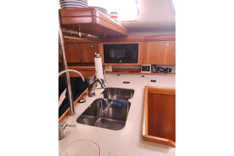 Slide: The Image of 2003 Hunter 386 yacht kitchen with sink, microwave, and wooden cabinetry. - 9