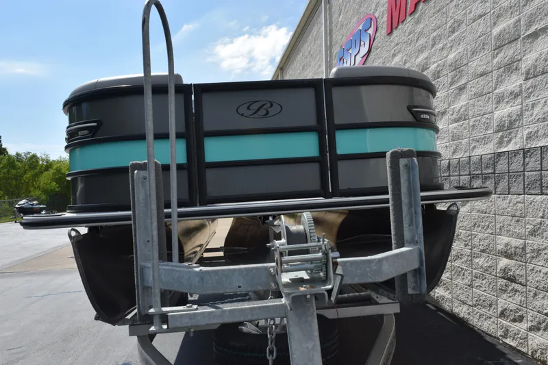 Slide: The Image of 2026 Bentley Pontoons Elite 223 Swingback on trailer, parked near a building. - 3