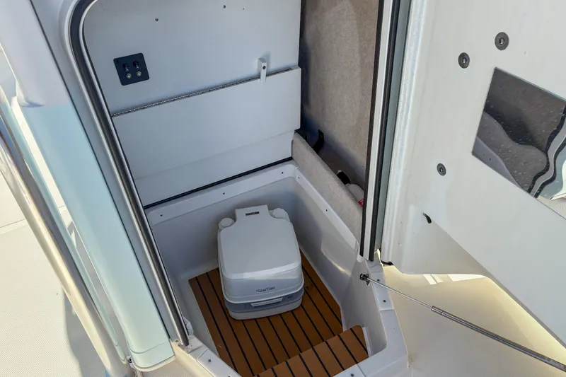 Slide: The Image of 2019 Ranger 2510 Bay boat interior with portable toilet and wooden flooring. - 13
