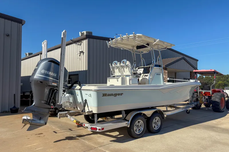 Slide: The Image of 2019 Ranger 2510 Bay boat on trailer with Yamaha outboard motor, parked near buildings. - 3