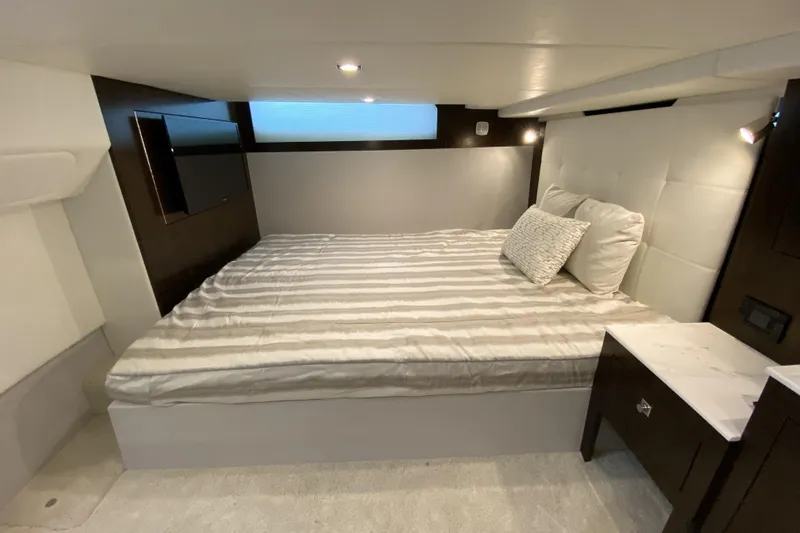 Slide: The Image of 2021 Cruisers Yachts 390 Express Coupe cabin with bed, TV, and modern decor. - 11