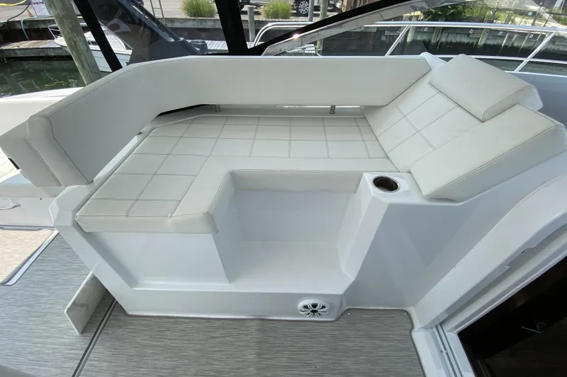 Slide: The Image of 2021 Cruisers Yachts 390 Express Coupe interior seating with white upholstery and cup holder. - 5