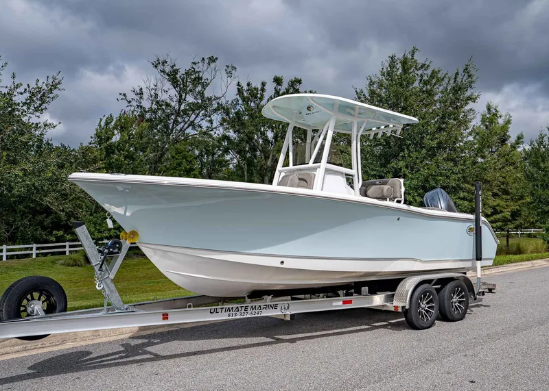 The Image of 2026 Sea Hunt Ultra 229 boat on trailer, parked on a road with trees in background. - 1