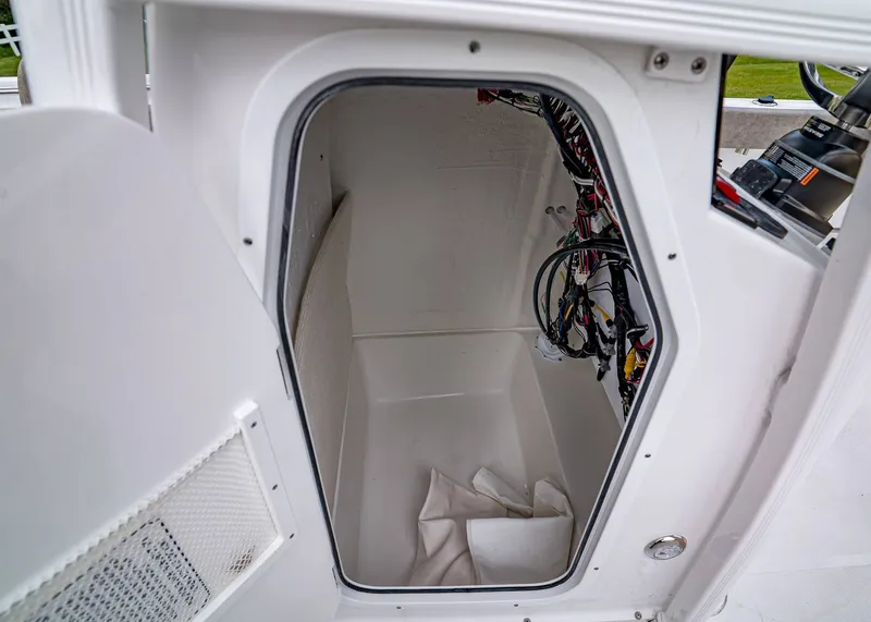 Slide: The Image of 2026 Sea Hunt Ultra 229 storage compartment with wiring and open door. - 17