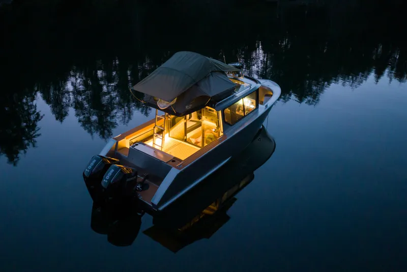 Slide: The Image of Jasper Marine Defender 22 boat, 2026 model, illuminated on calm water at dusk. - 16