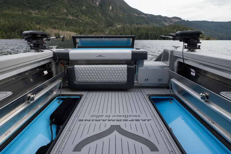 Slide: The Image of 2026 Jasper Marine Defender 22 boat interior with modern seating and storage, set on a scenic lake. - 18