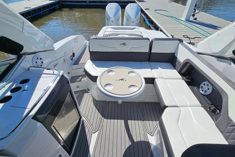 Slide: The Image of 2019 Monterey 305SS Super Sport boat interior with seating and table, docked by the water. - 16