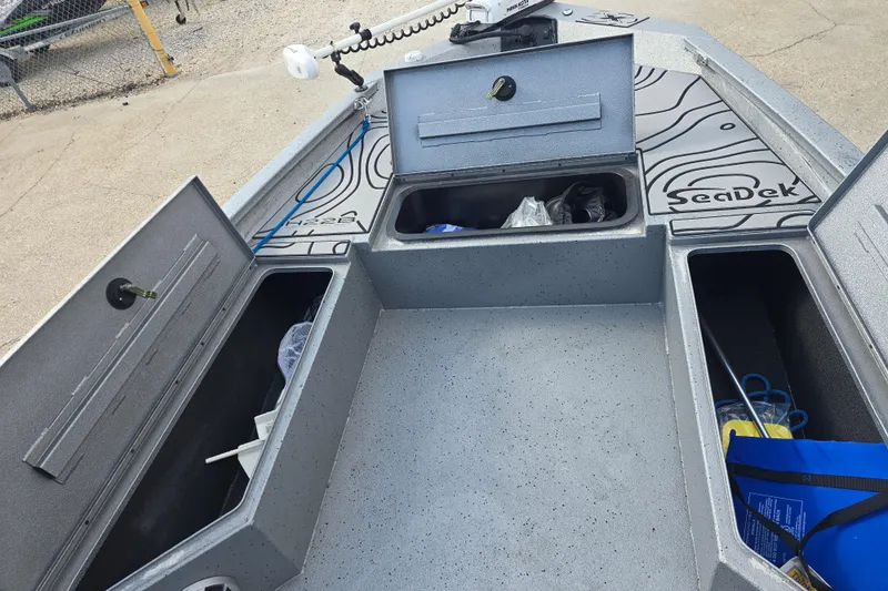 Slide: The Image of 2024 Xpress H22B Bay boat storage compartments with SeaDek flooring, open hatches, and fishing gear. - 11
