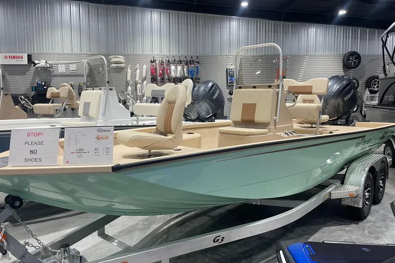 Slide: The Image of 2024 G3 Bay 20 GX boat on display in showroom, featuring beige seating and Yamaha engines. - 0
