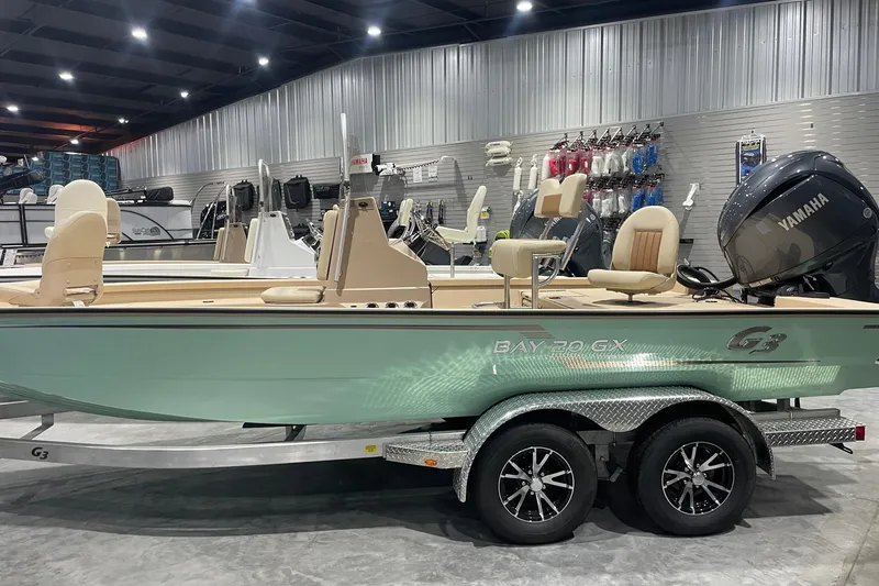 Slide: The Image of 2024 G3 Bay 20 GX boat in showroom, featuring Yamaha engine and dual-axle trailer. - 1