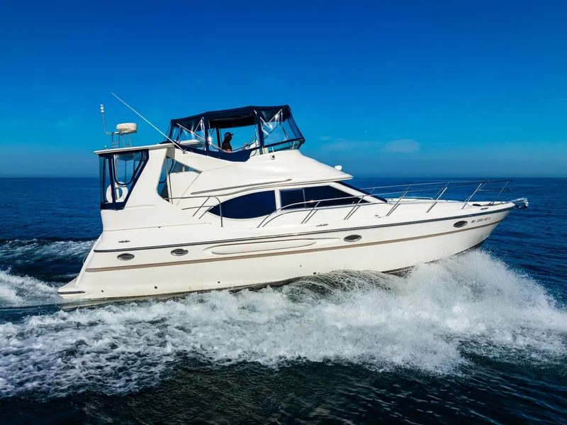 Slide: The Image of 1999 Maxum 4100 SCA Motor Yacht cruising on open water under clear blue skies. - 10
