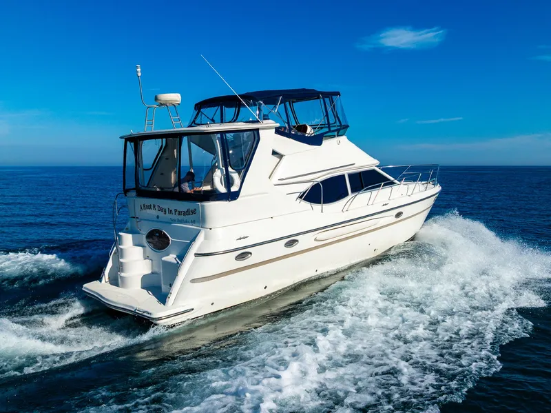 Slide: The Image of 1999 Maxum 4100 SCA Motor Yacht cruising on open water under clear blue skies. - 11