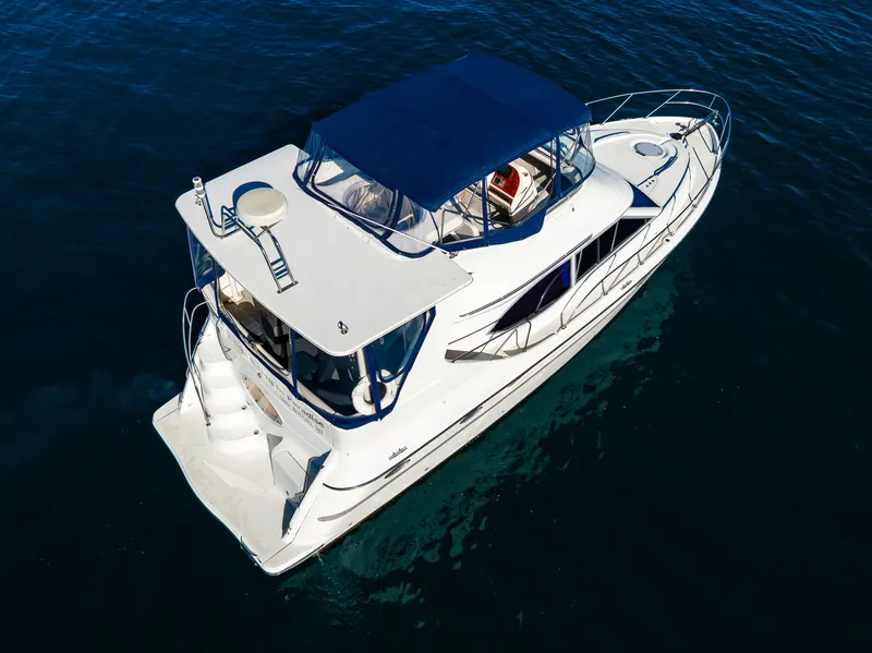 Slide: The Image of 1999 Maxum 4100 SCA Motor Yacht with blue canopy on calm water. - 5