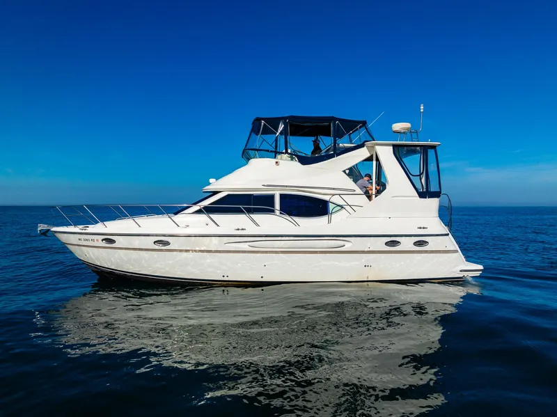 Slide: The Image of 1999 Maxum 4100 SCA Motor Yacht on calm blue waters under clear sky. - 8