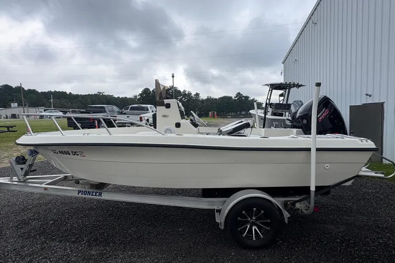 Slide: The Image of 1999 Sea Pro 180 Center Console boat on trailer, parked outdoors near a building. - 2