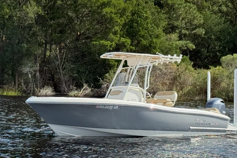 Slide: The Image of 2020 Pioneer 202 Islander boat on water, surrounded by lush green trees. - 2