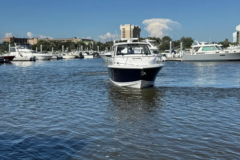 Slide: The Image of 2026 Pursuit OS 355 Offshore boat cruising in a marina under a clear blue sky. - 2