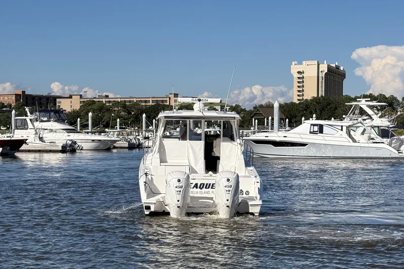Slide: The Image of 2026 Pursuit OS 355 Offshore boat cruising in a marina with cityscape background. - 7