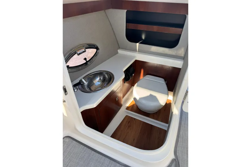 Slide: The Image of 2019 Chaparral 297 SSX boat interior with sink and toilet in compact bathroom. - 9