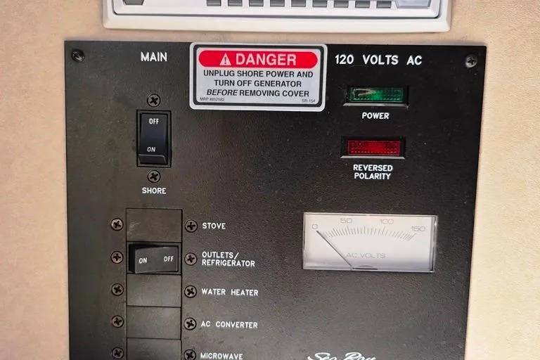Slide: The Image of Electrical panel of 1997 Sea Ray 240 Sundancer with warning label and power switches. - 11