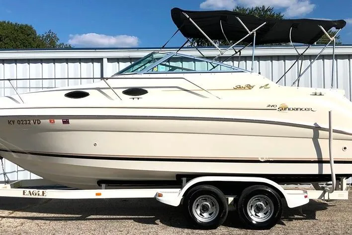 Slide: The Image of 1997 Sea Ray 240 Sundancer boat on trailer, parked outdoors with blue sky background. - 15
