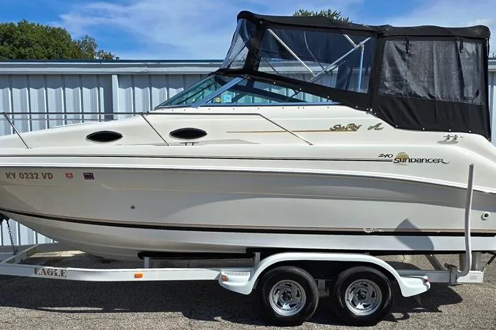 Slide: The Image of 1997 Sea Ray 240 Sundancer boat on trailer, with black canopy, parked outdoors. - 16
